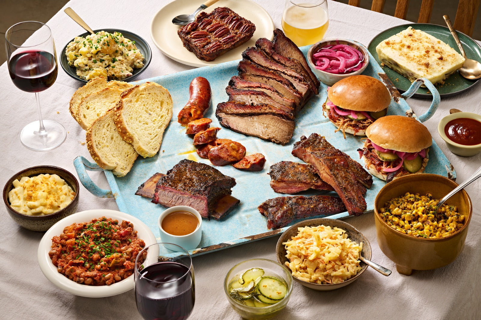 A Texas BBQ feast — brisket, ribs and smoked sausages with sides on a wooden board.